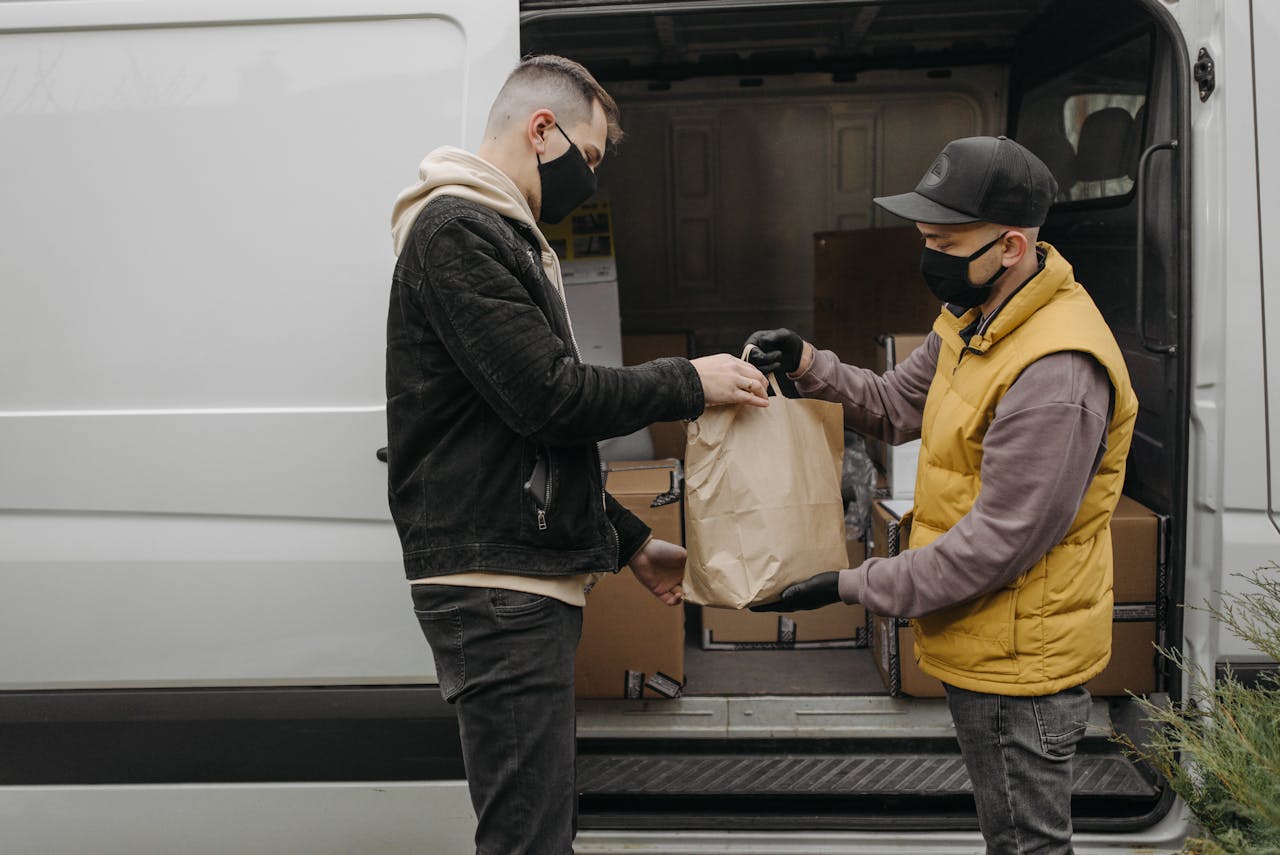 Crafting Captivating Headlines: Your awesome post title goes here Masked deliveryman hands package to customer from van, ensuring safety and hygiene.